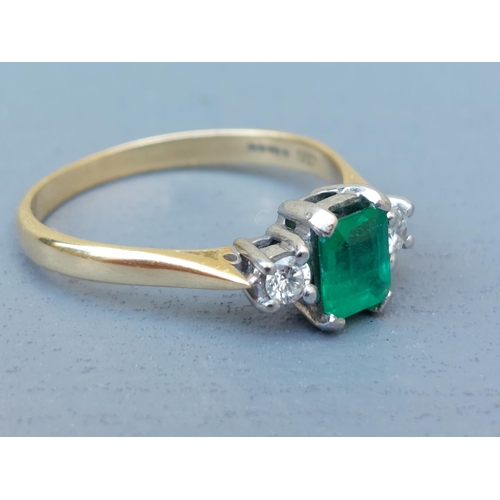 260 - A modern three stone emerald & diamond 18ct gold ring, the four-claw set rectangular cut emerald wei... 