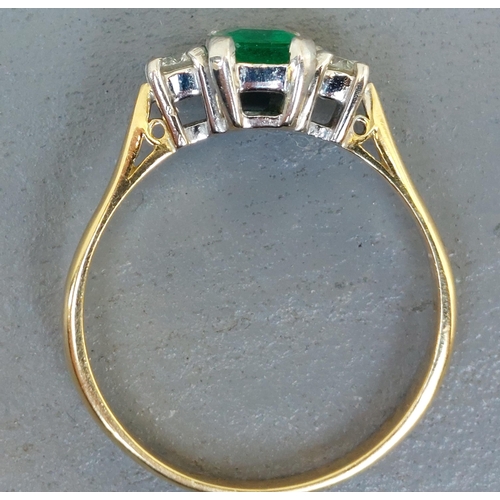 260 - A modern three stone emerald & diamond 18ct gold ring, the four-claw set rectangular cut emerald wei... 