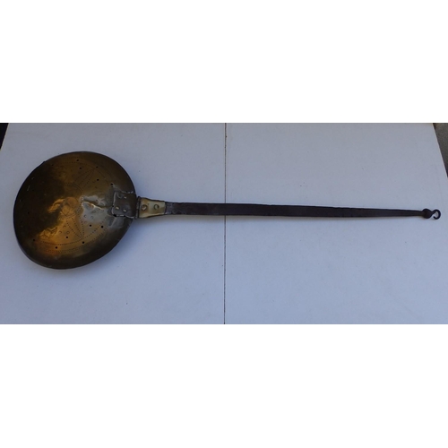 81 - An antique brass warming pan with iron strap handle, the pan pricked with a geometric floral design,... 