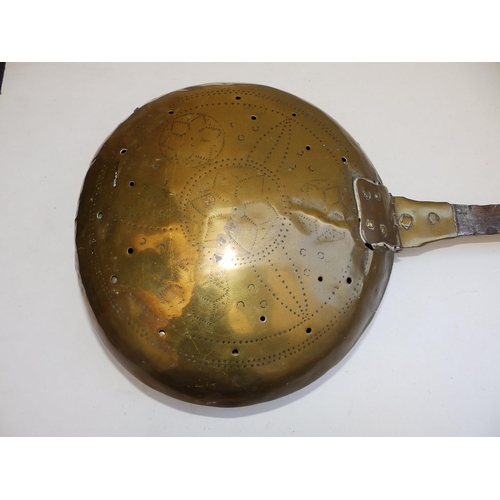 81 - An antique brass warming pan with iron strap handle, the pan pricked with a geometric floral design,... 