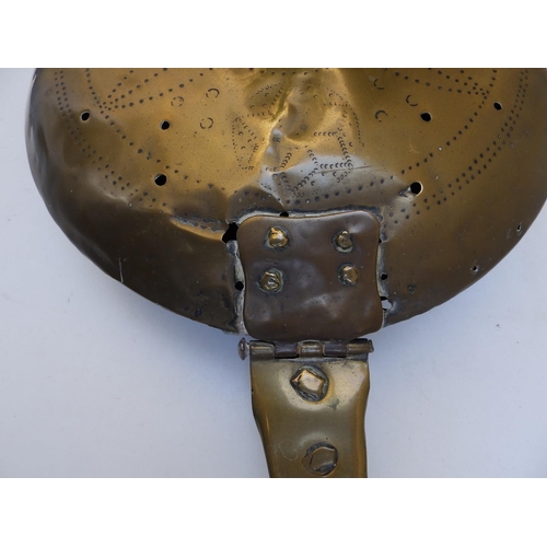 81 - An antique brass warming pan with iron strap handle, the pan pricked with a geometric floral design,... 