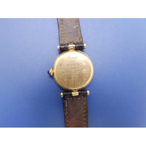 127 - A ladies gold plated Cartier Vermeil Quartz wrist watch with black dial devoid of hour markers, sapp... 