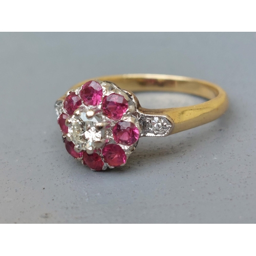 157 - A ruby & diamond cluster ring, small diamonds to shoulders, on '18ct' shank.  Finger size O.