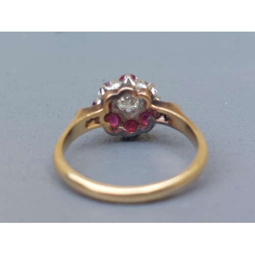 157 - A ruby & diamond cluster ring, small diamonds to shoulders, on '18ct' shank.  Finger size O.