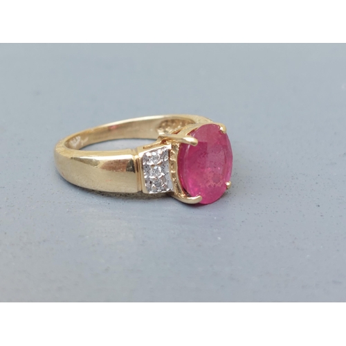 161 - A modern ruby & diamond set 18ct gold ring, having oval cut ruby to centre.  Finger size J.