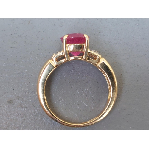 161 - A modern ruby & diamond set 18ct gold ring, having oval cut ruby to centre.  Finger size J.