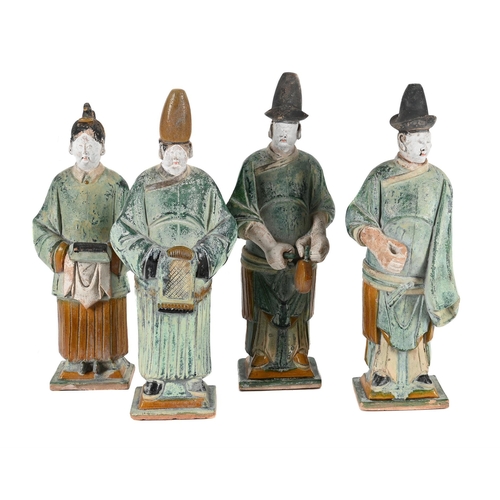 766 - FOUR CHINESE POTTERY FIGURES OF ATTENDANTSMING DYNASTYIn green and okra glazes and white painted det... 