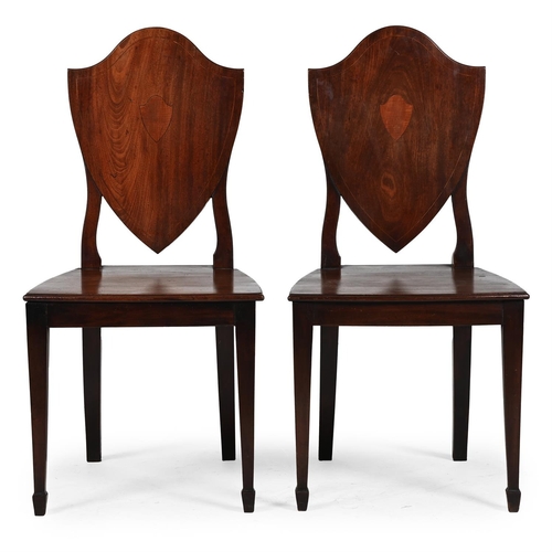 304 - A PAIR OF GEORGE III MAHOGANY SHIELD BACK HALL CHAIRSCIRCA 1790The line inlaid backs centred with a ... 