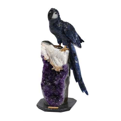 783 - A CARVED SEMI PRECIOUS STONE MODEL OF A PARROTMODERNPerched atop a part amethyst geode formation, th... 