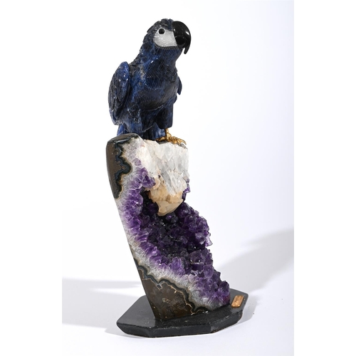 783 - A CARVED SEMI PRECIOUS STONE MODEL OF A PARROTMODERNPerched atop a part amethyst geode formation, th... 