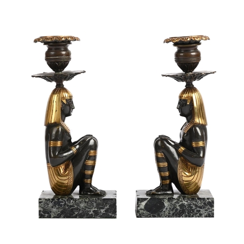 115 - A PAIR OF EGYPTIAN REVIVAL BRONZE AND PARCEL GILT CANDLESTICKS 20TH CENTURY Marble bases 29cm high, ... 