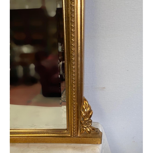 108 - A GOOD QUALITY GILT OVER-MANTLE / HALL MIRROR, with curved top, having a central foliage decoration,... 