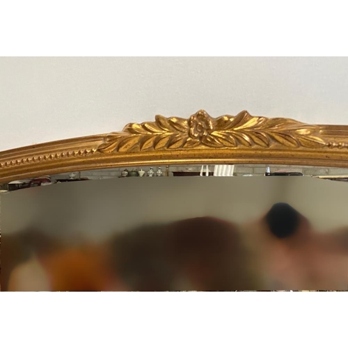 108 - A GOOD QUALITY GILT OVER-MANTLE / HALL MIRROR, with curved top, having a central foliage decoration,... 