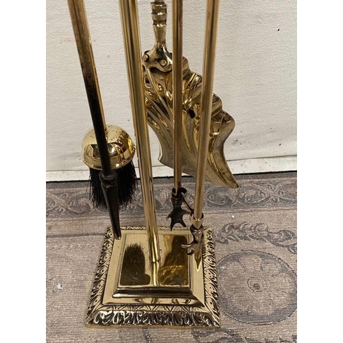 189 - A FOUR PIECE BRASS FIRE IRON SET, with shovel, brush, poker and tongs, all on a stand, the base of w... 