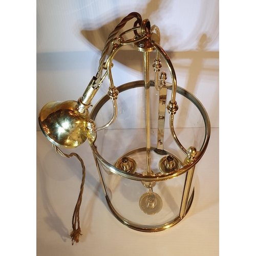 210 - A GOOD QUALITY POLISHED BRASS HANGING LANTERN with curved glass shade, holds three bulbs, with short... 