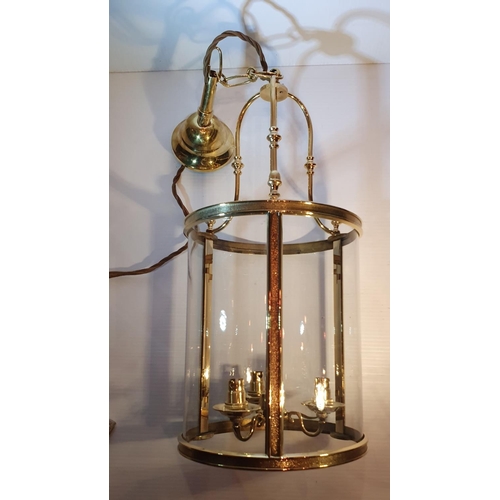 210 - A GOOD QUALITY POLISHED BRASS HANGING LANTERN with curved glass shade, holds three bulbs, with short... 