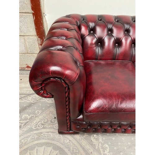 212 - A THREE SEATER CHESTERFIELD STYLE COUCH, in oxblood colour with buttoned detail to the back and side... 