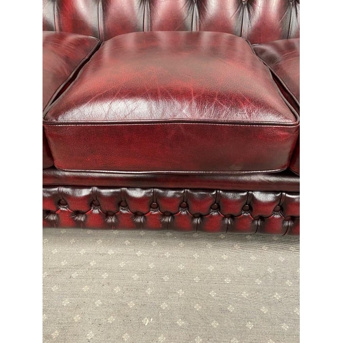 212 - A THREE SEATER CHESTERFIELD STYLE COUCH, in oxblood colour with buttoned detail to the back and side... 