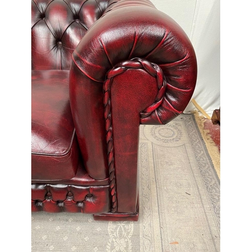 212 - A THREE SEATER CHESTERFIELD STYLE COUCH, in oxblood colour with buttoned detail to the back and side... 