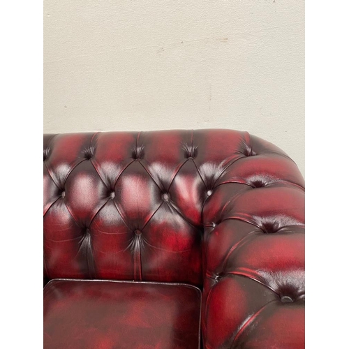 212 - A THREE SEATER CHESTERFIELD STYLE COUCH, in oxblood colour with buttoned detail to the back and side... 