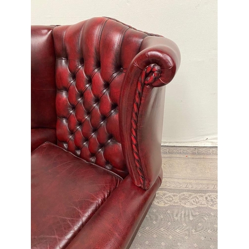 215 - A GOOD QUALITY OX BLOOD LEATHER WING BACK RECLINER ARMCHAIR, with deep buttoned back, and rope detai... 