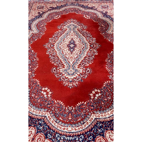 237 - A LARGE FLOOR RUG, with main ground red, having dense motif of foliage and floral designs, with a ce... 