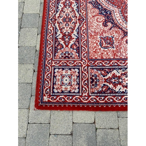 237 - A LARGE FLOOR RUG, with main ground red, having dense motif of foliage and floral designs, with a ce... 