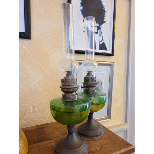 238 - A PAIR OF PAROFIN LAMPS, with green glass reservoir and brass column and fitting, clear glass chimne... 