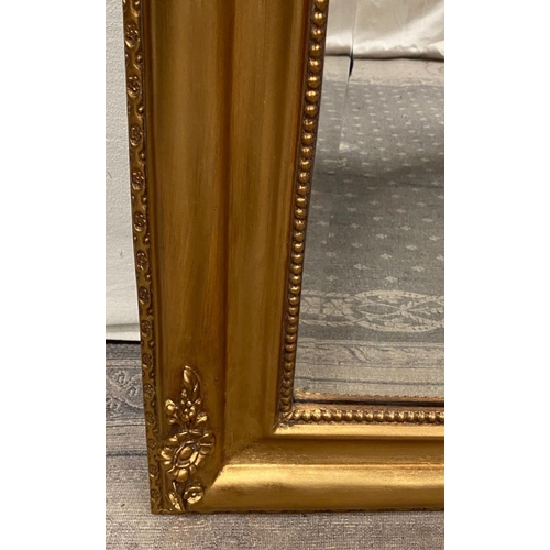 79 - A VERY FINE GILT OVER-MANTLE WALL MIRROR, with floral design to the curved top corners and a bead tr... 