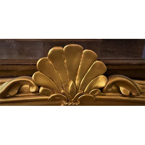 177 - A 19TH CENTURY GILTWOOD OVERMANTLE / OVER CONSOLE MIRROR; arched top surmounted by a prominent clams... 