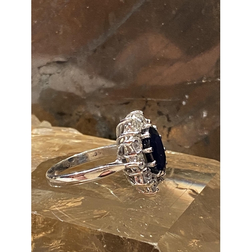 93 - AN 18CT WHITE GOLD SAPPHIRE & DIAMOND CLUSTER RING, with a central oval shaped sapphire stone weighi... 