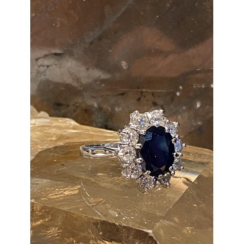 93 - AN 18CT WHITE GOLD SAPPHIRE & DIAMOND CLUSTER RING, with a central oval shaped sapphire stone weighi... 