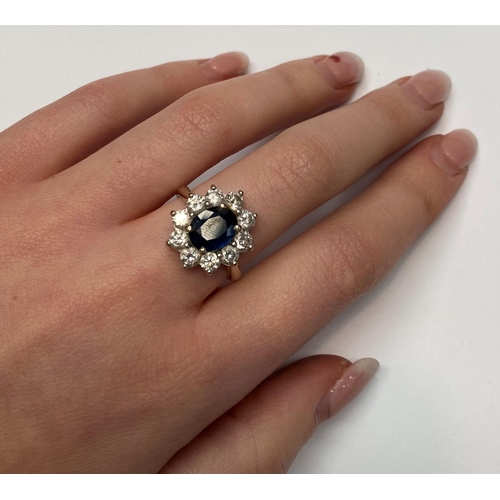 93 - AN 18CT WHITE GOLD SAPPHIRE & DIAMOND CLUSTER RING, with a central oval shaped sapphire stone weighi... 