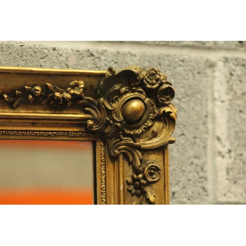 104 - AN ANTIQUE GILT WALL MIRROR, 	shaped in a rectangular form; this gilt mirror is beautifully adorned ... 