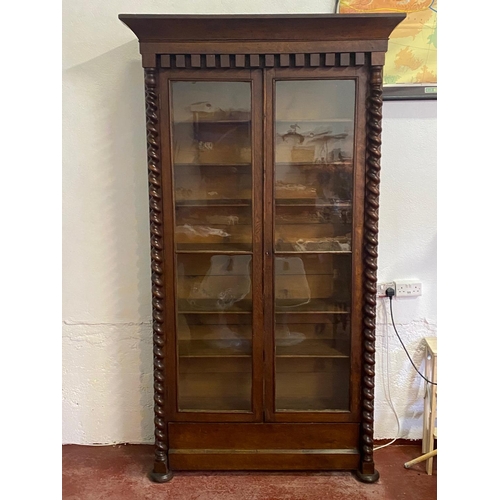 120 - A 19TH CENTURY IRISH OAK TWO DOOR GLAZED CABINET, with a tapered pediment over a line of bold dentil... 