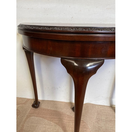 124 - A GOOD MAHOGANY DEMI LUNE FOLD OVER CARD TABLE, with gadrooned edge, standing on claw and ball feet.... 