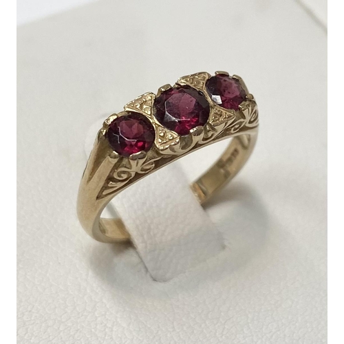 182 - A 9CT YELLOW GOLD THREE STONE GARNET RING, the garnets are set in a super detailed mount , ring size... 