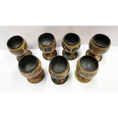 211 - A SET OF SEVEN HARDWOOD CARVED PAINTED EGG CUPS, numbered to base, along with a wooden painted Russi... 