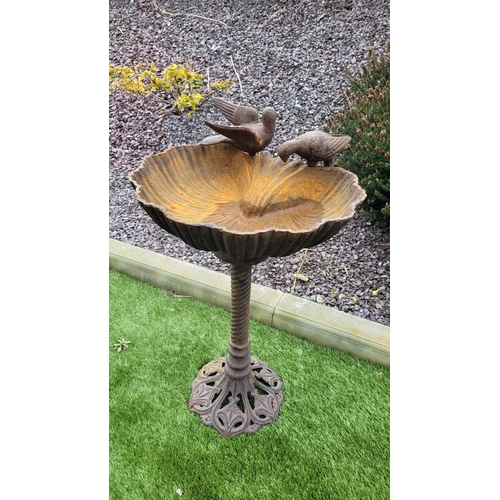 220 - A RUST COLOURED GARDEN BIRD BATH, 	the shell shaped top stands upon a barley twist column support te... 