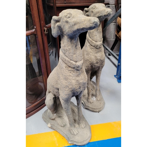 221 - A PAIR OF STONE COMPOSITE GARDEN ORNAMENTS IN THE FORM OF TWO SEATED HOUNDS, each with a collar. Dim... 