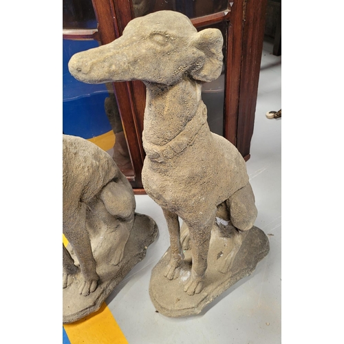 221 - A PAIR OF STONE COMPOSITE GARDEN ORNAMENTS IN THE FORM OF TWO SEATED HOUNDS, each with a collar. Dim... 