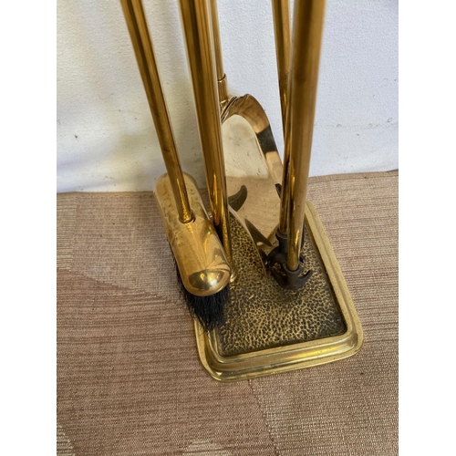 246 - A SET OF FOUR BRASS FIRE IMPLEMENTS ON STAND, to include shovel, brush, poker and tongs, each with d... 