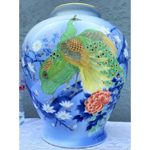 29 - A VIBRANT POT SHAPED PORCELAIN VASE, decorated with brightly coloured peacocks and blossoms on a lig... 