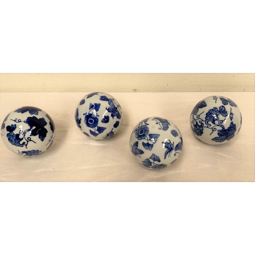 136 - A SET OF FOUR CHINESE CARPET BALLS, finely decorated with cobalt blue floral designs on white ground