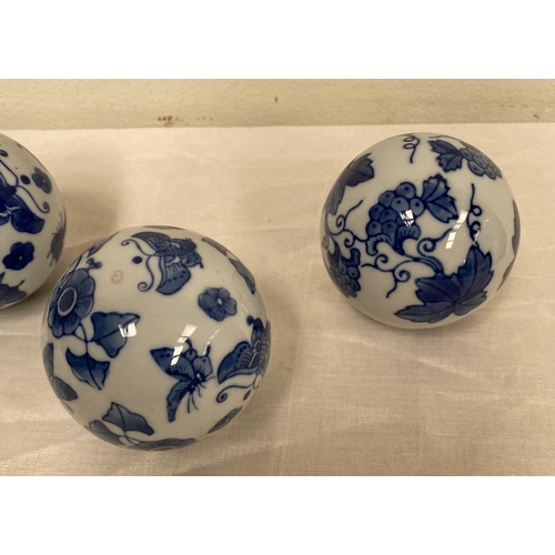 136 - A SET OF FOUR CHINESE CARPET BALLS, finely decorated with cobalt blue floral designs on white ground