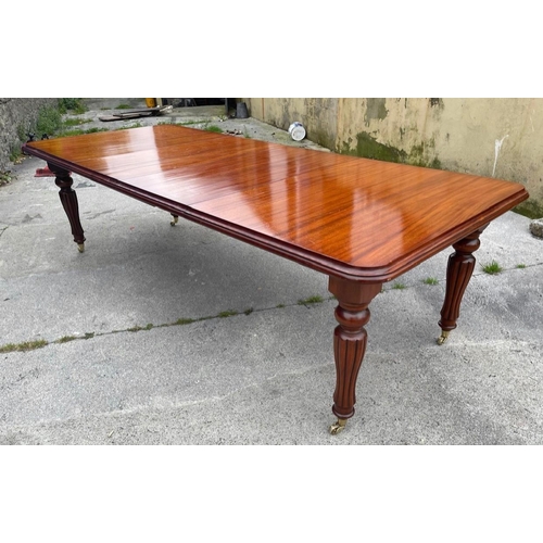 35 - A MAHOGANY TWO LEAF REGENCY STYLE DINING/BOARDROOM TABLE, by William Tillman London, with fluted leg... 