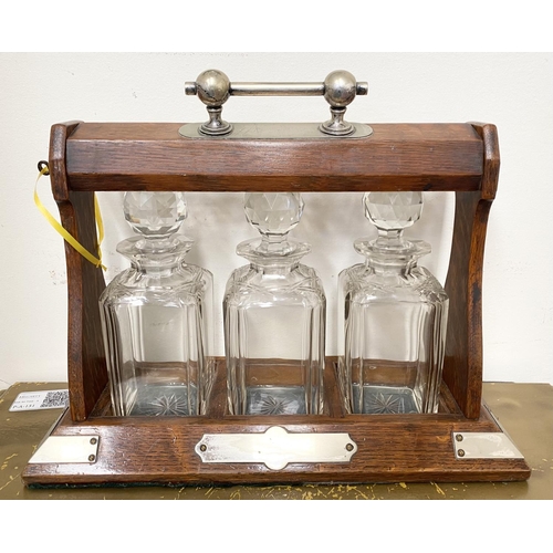 45 - AN ANTIQUE THREE BOTTLE TANTULUS, with three cut glass decanters/carafes, within oak frame with silv... 