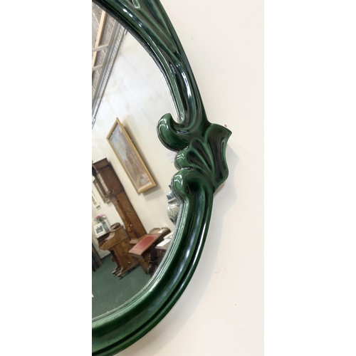 50 - AN ART NOUVEAU CERAMIC OVAL WALL MIRROR, fluted green ceramic frame with scrolling details, Dimensio... 