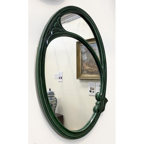 50 - AN ART NOUVEAU CERAMIC OVAL WALL MIRROR, fluted green ceramic frame with scrolling details, Dimensio... 