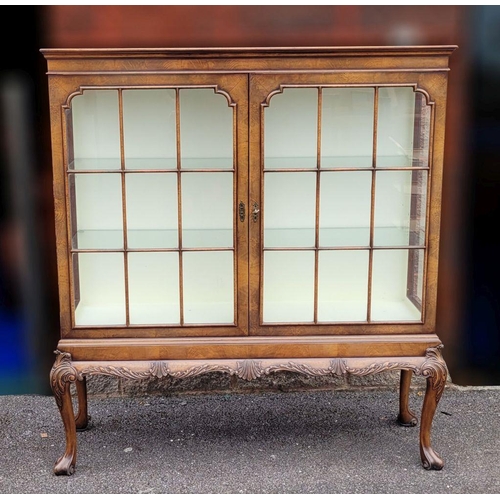 114 - A GOOD QUALITY TWO DOOR GLAZED CABINET, raised on a nice decorative scrolling carved leg, with carve... 